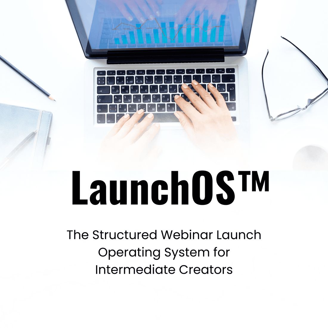 Laptop with hands on keyboard, glasses, and notebook on a white surface with &